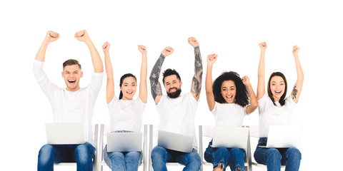 Obraz premium multiethnic group of people using laptops and rejoicing with hands above head isolated on white