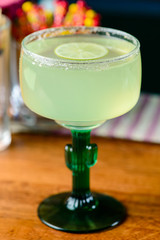 margarita cocktail closeup on bar counter in a margagita glass with lime