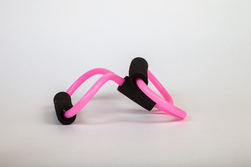 Pink rubber tube expander with black paralon handles for performing fitness exercises with hands on a white isolated background