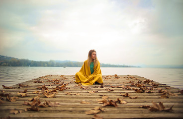 Girl sitting on a pier, looking the horizon