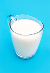 Glass cup of milk on blue background.
