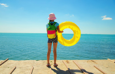 Little girl with swim ring standing on the seashore