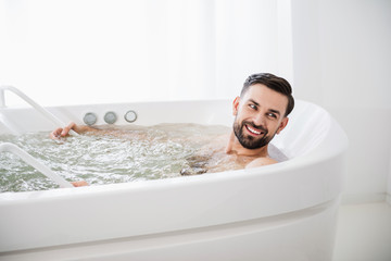 Emotional man smiling while being in hydro massage bathtub