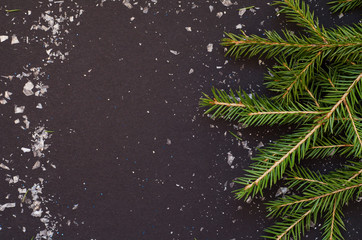 Fototapeta na wymiar Christmas frame made from pine branch and snowflakes on black background.