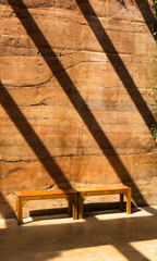 long wooden chair on  stone wall