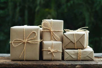 Stack of simple eco friendly gift box package wrap with brown paper in old wooden table background, green present concept - 240009244