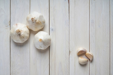 Still life of a heads and a cloves of garlic on a white wooden table