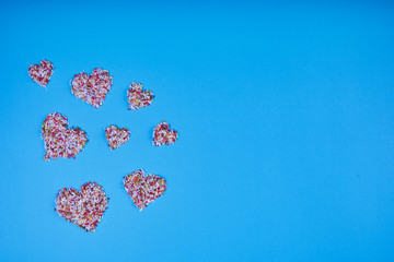 Multicolored confectionery noodle hearts on blue background. St. Valentine's Day