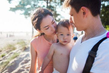 Portrait of happy young family with charming baby. Picnic on the beach