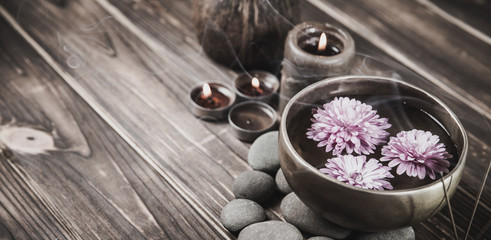 Singing bowl with candles with pebbles on dark wooden background