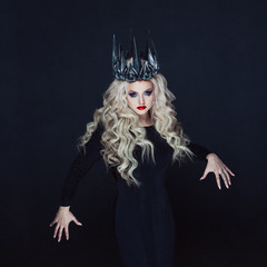 Portrait of a Gothic Princess. Beautiful young blonde woman in metal crown and black cloak.
