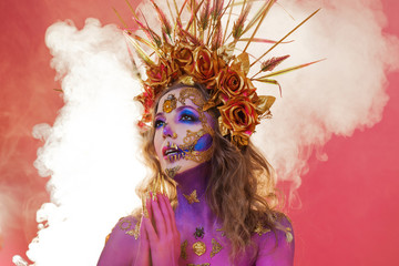 Bright Halloween image, Mexican style with sugar skulls on face. Young beautiful woman bright pink...
