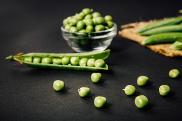 Pods of green peas and pea on a dark background.