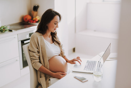 Concentrated young woman looking at monitor and typing at keyboard