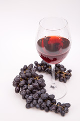 A bunch of grapes and a glass of wine.