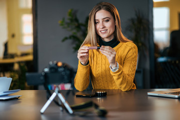 Sharing experience. Young woman making a video for her blog on cosmetics.