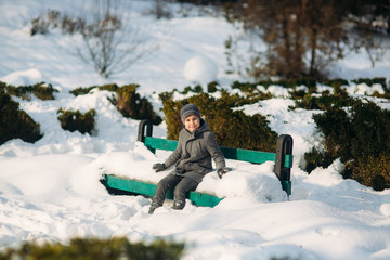Little boy sit on the bench in winter weather
