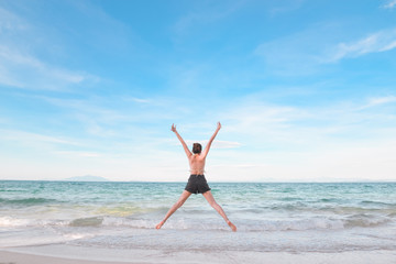 Outdoor summer portrait of young pretty woman looking to the ocean at tropical beach, enjoy her freedom and fresh air, wearing stylish hat and bikini