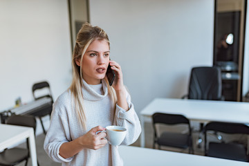 Serious business woman talking on the phone on coffee break.