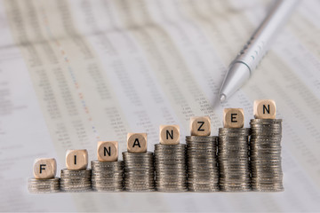 Stacked euro coins with cubes on them and the word Finances in German. Concept: finances and bussines