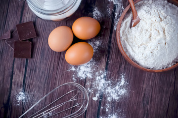 Products and objects for baking chocolate cake on dark wooden table. Concept of home baking.