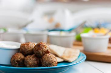 Fried meat balls with mint and apple with white sauce and flat cakes - traditional Greek lunch on a blue plate in a restaurant