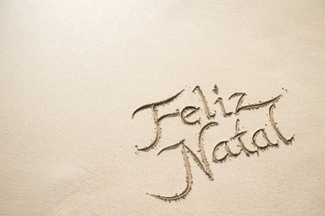 Feliz Natal (Merry Christmas in Portuguese) message handwritten on a sand beach in Rio de Janeiro, Brazil