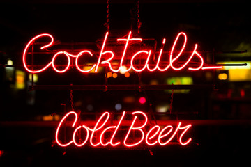 Vintage ocktails and cold beer neon sign hanging in a bar window