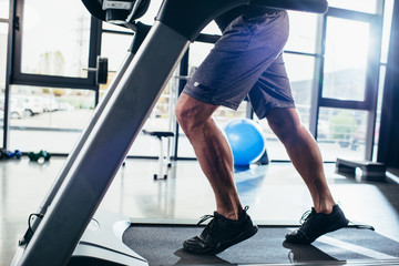 Fototapeta na wymiar cropped image of sportsman running on treadmill in gym