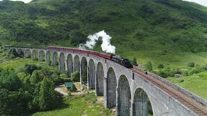 Drone shot of classic steam train crossing the famous Glenfinnan viaduct, travel and tourism Scotland