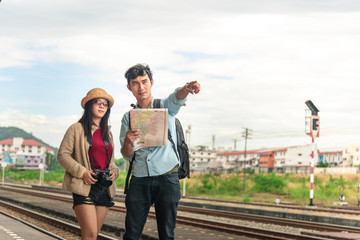 Multiethnic friends, backpack travelers, or college students using local map navigation together at train station platform. Asia travel destination, tourism activity, or railroad trip concept