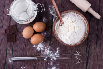 Products and objects for baking chocolate cake on dark wooden table. Concept of home baking.
