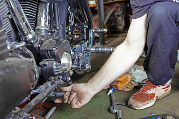 Side view portrait of man working in garage repairing motorcycle