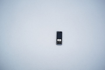 Mobile phone lying on a white snow background.