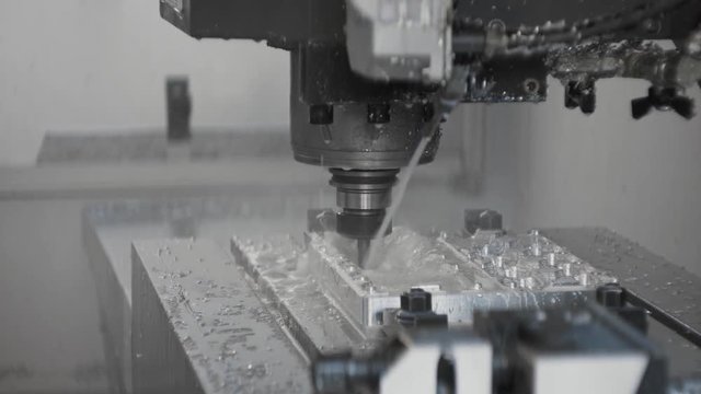 Cnc metal working machine with cutter tool luminium detail milling at factory. Tech process of metalwork and machine manufacturing of press form close up. Precision milling work. Slowmotion, closeup