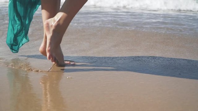 Female bare feet walking on the wet sand on the beach. Slow motion