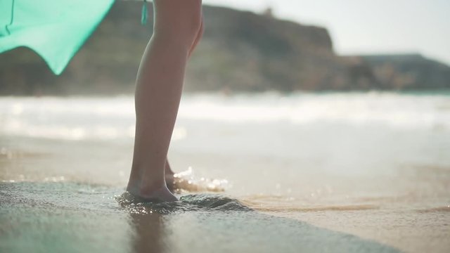Female bare feet standing on the wet sand on the beach. Female legs posing in the sun at a seaside resort.