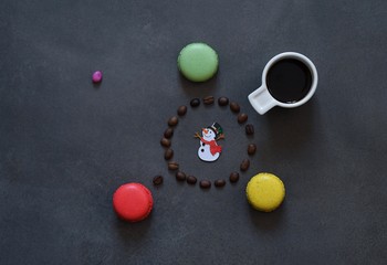 Fototapeta na wymiar A cup of hot coffee, colored cookies and coffee beans 