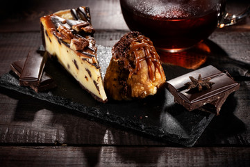 Anthill cake and cheese cake with chocolate and condensed milk on a wooden table. Low key.