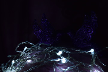 Two beautiful violet birds Christmas tree toys in the dark sparkle, shine, look at each other in the background white lights
