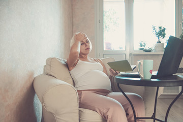 Young beautiful pregnant woman working on laptop. Pregnant business woman searching information and...