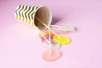 multi-colored lollipops on a pink background in a paper golden cup