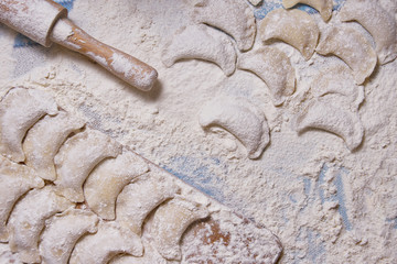 Dumplings with rolling pin on table sprinkled with flour