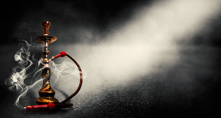 Dark black background of smoking hookah on the concrete floor, in clouds of smoke and neon light