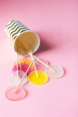 multi-colored lollipops on a pink background in a paper golden glass