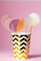 multi-colored lollipops on a pink background in a paper golden cup, 
