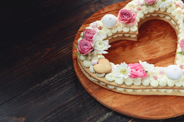 Valentine's Day heart-shaped cake with flowers as decoration. The concept of a gift to a loved one on a holiday.