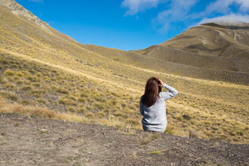 Hipster girl traveller at yellow hill Lindis Pass, New Zealand. .