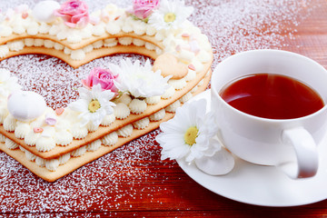 Valentine's Day heart-shaped cake with flowers as decoration. The concept of a gift to a loved one on a holiday.