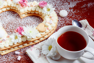 Valentine's Day heart-shaped cake with flowers as decoration. The concept of a gift to a loved one on a holiday.